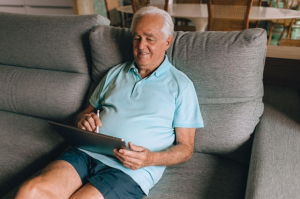 Anziano sul divano con tablet